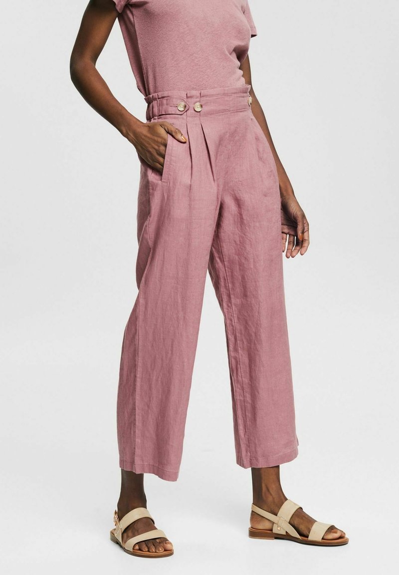 Lichtroze linnen broek met een hoge taille, wijde pijpen, plooien aan de voorkant en twee zijzakken, versierd met twee knopen op de taille.