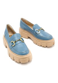 Niebieskie skórzane mokasyny z grubą beżową podeszwą. Posiadają dekoracyjną klamrę w kolorze złota. Gładka faktura i zaokrąglony kształt.
