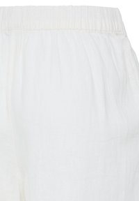 Pantalon blanc à taille élastique, en tissu léger légèrement texturé avec un détail froncé près de la taille.