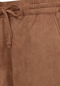 Brown suede-textured pants with an elastic waistband and tied drawstring on the left side.