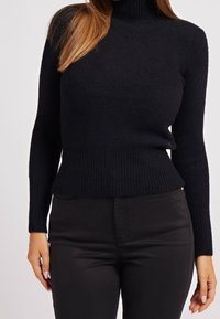 Musta pooloneulepusero, joka on valmistettu pehmeästä, teksturoidusta kankaasta, jossa on resorit hihansuissa ja helmassa, yhdistettynä mustiin istuviin housuihin.