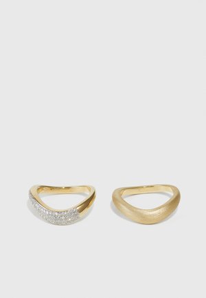 Gold rings with curved designs; one features a textured finish, and the other is adorned with sparkling stones along the band.