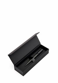 Stylo noir avec une prise texturée placé à l'intérieur d'une boîte-cadeau rectangulaire noire mate, avec un fermoir en ruban et un intérieur doux.