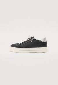 Baskets en cuir noir avec semelle blanche, présentant un accent argenté à l'arrière, des lacets contrastants et un détail de fermeture éclair sur le côté.