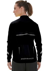 Svart idrottsjacka med långa ärmar, reflexstripes och en logo. Har en figursydd design och ett strukturerat material för komfort.