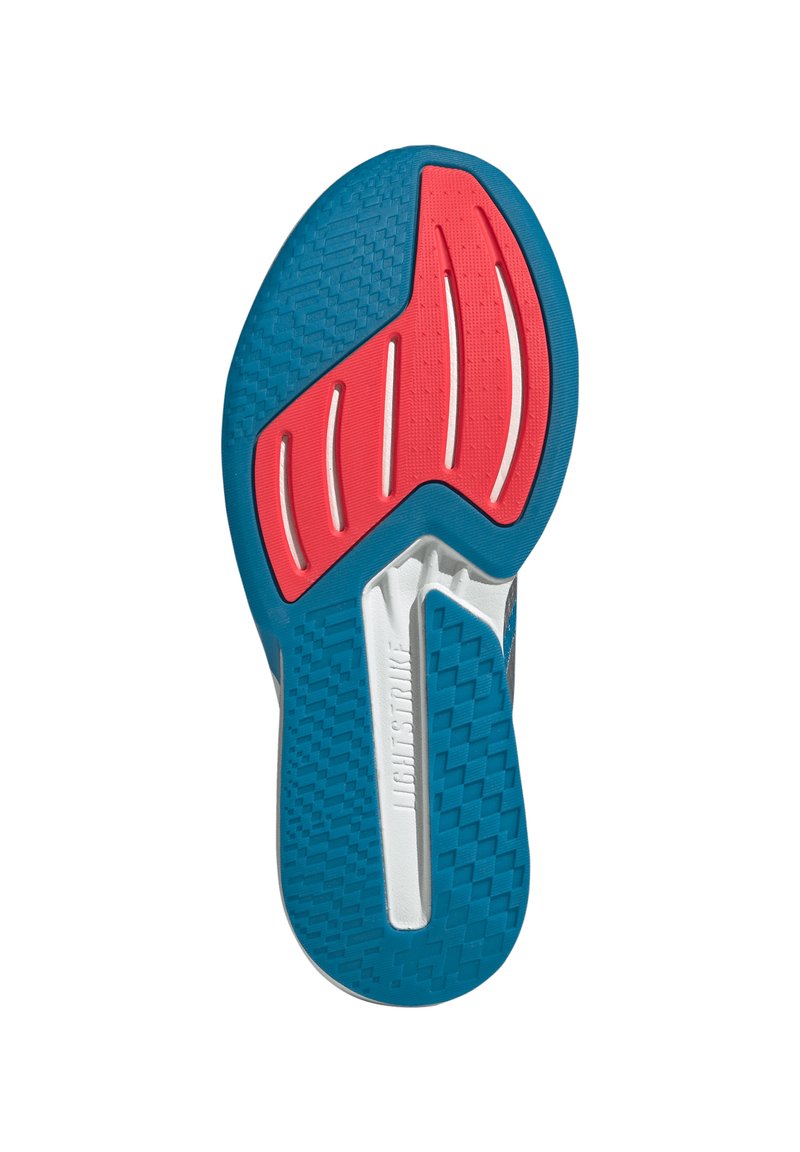 Sole of a shoe featuring a textured blue rubber base, red accents, and white grooves for traction. Distinct geometric patterns are visible.
