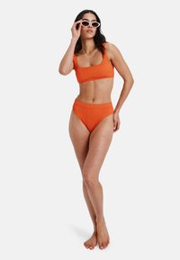 Set de bikini cu dungi portocalii, cu decolteu pătrat și slip cu talie înaltă, asortat cu ochelari de soare albi în formă de ochi de pisică. Textură netedă.
