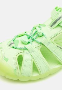 Hellgrüne Sport-Sandale mit offenem Zehenbereich, verstellbaren elastischen Schnürsenkeln, Riemenschlüssen und atmungsaktivem ausgeschnittenem Design.