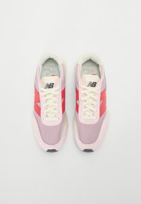 Baskets légères avec une tige en mesh rose et rouge, des lacets crème et une semelle rembourrée. Marquages distinctifs sur la languette et les côtés.