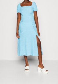 Niebieska midi sukienka z kwadratowym dekoltem, bufiastymi rękawami i bocznym rozcięciem. Posiada subtelny wzór kwiatowy oraz gładką teksturę materiału.