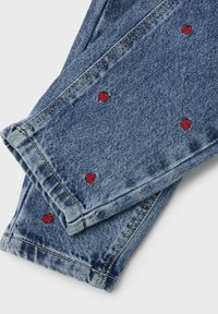 Jeans de mezclilla con un lavado azul claro, con bordados en forma de corazón rojo dispersos por la tela. Diseño clásico de cinco bolsillos.