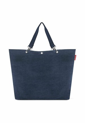 Grote marineblauwe draagtas met dubbele banden en metalen oogjes, met een klein rood merkembleem aan de rechterbovenkant.