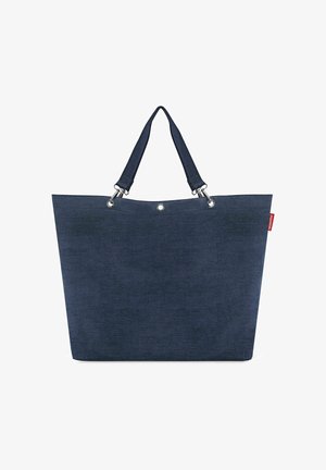 Große dunkelblaue Tragetasche mit doppelt gearbeiteten Trägern und Metallösen, mit einem kleinen roten Markenschild oben rechts.