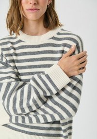 Sweter w paski w odcieniach kremu i szarości, wykonany z miękkiego materiału, z prążkowanym okrągłym dekoltem i mankietami, z szerokimi poziomymi pasami.