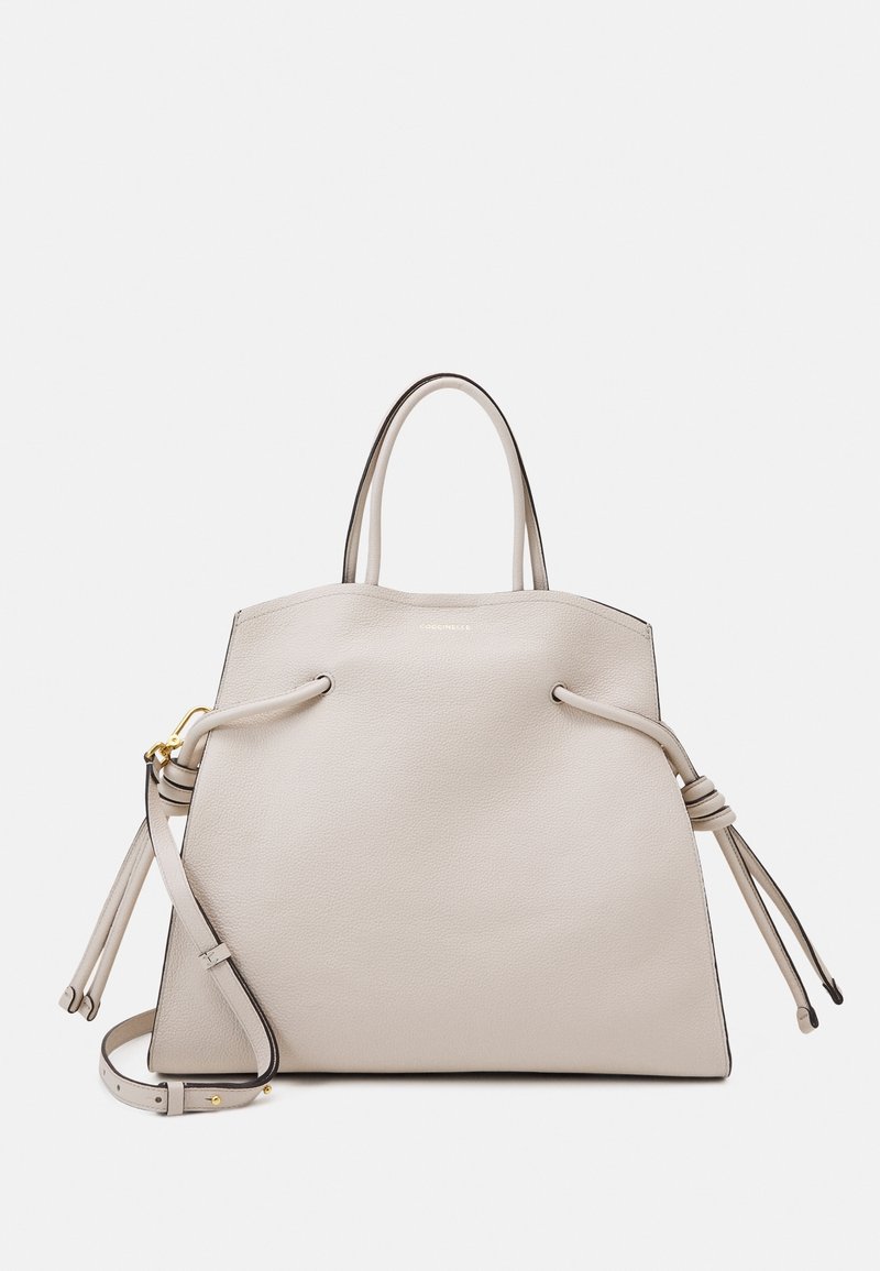 Beige läder tote-väska med en strukturerad form, smal topp, två sidodragband och en avtagbar axelrem. Guldhardware-accent.