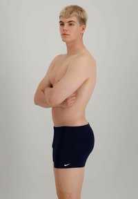 Sötétkék fürdőnadrág, karcsú szabással. Simaságú anyagból készült, a bal oldalon egy kis fehér Nike logóval.