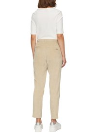 Beige corduroy broek met een rechte snit, voorzien van een achterzak en een elastische tailleband, gecombineerd met witte sneakers.