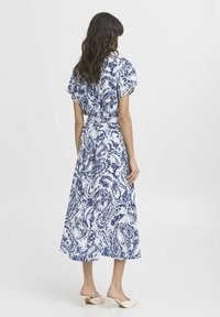 Rochie vaporoasă, de lungime medie, cu un model paisley alb și albastru, având mâneci scurte, talie strânsă și un material moale, ușor.