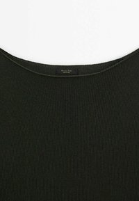 Gros plan du col d'un pull en maille côtelée noire avec une petite étiquette rectangulaire cousue à l'intérieur du col.