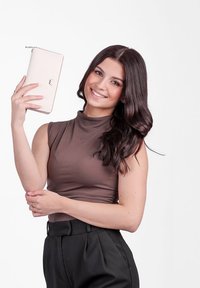 Růžová zipová peněženka držená v ruce, hladký syntetický materiál, minimalistický design s logem, na bílém pozadí.