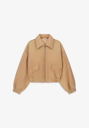Krótkia beżowa kurtka z miękkiego materiału z dużym kołnierzem, przednim zamkiem, dwoma dużymi kieszeniami z patkami oraz ściągaczami przy mankietach. Subtelne logo na piersi.