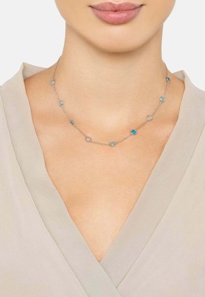 Silver necklace featuring alternating blue and clear circular gemstones on a delicate chain. The design is minimalistic and elegant.