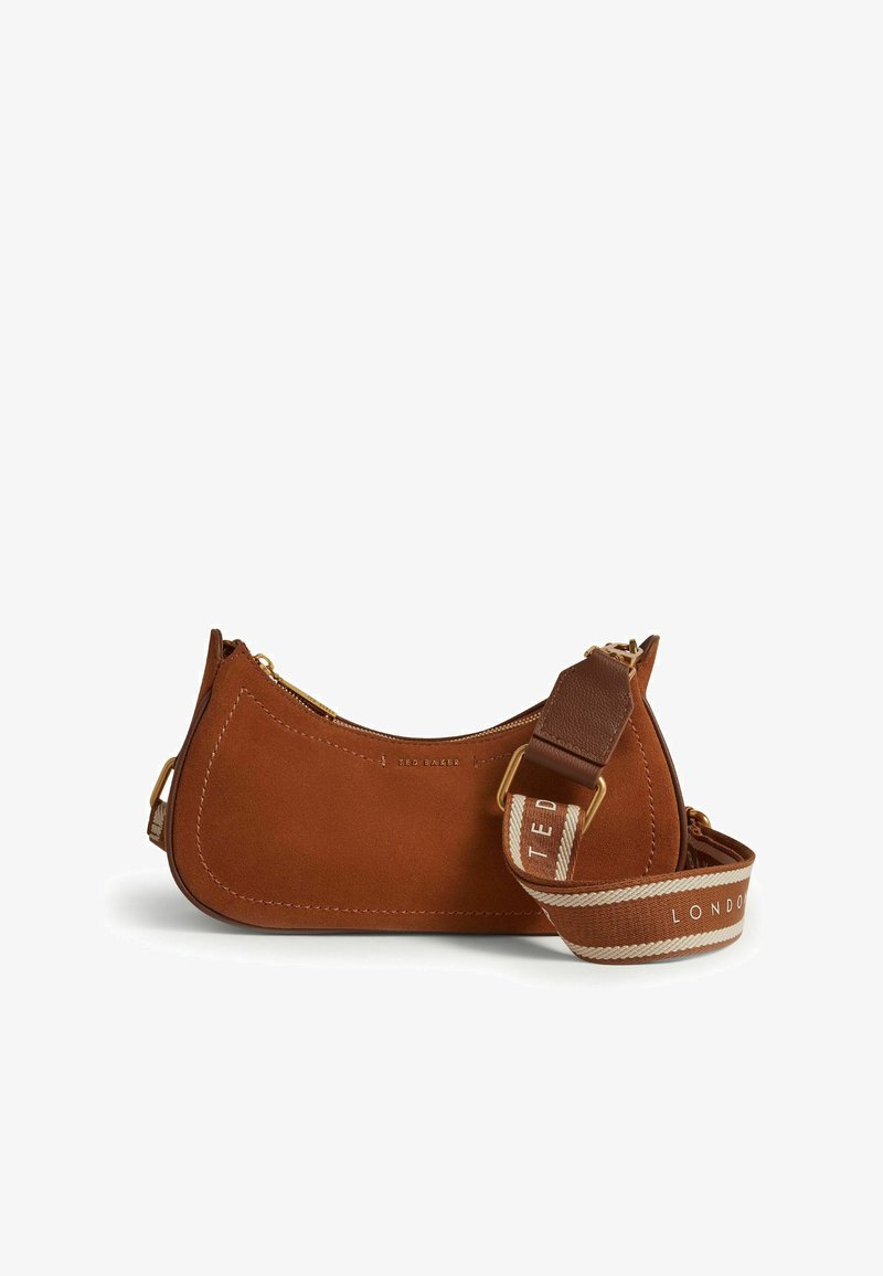 Sac à épaule en daim marron en forme de croissant avec une large bandoulière ajustable portant le texte "Ted Baker London" et une fermeture éclair dorée.