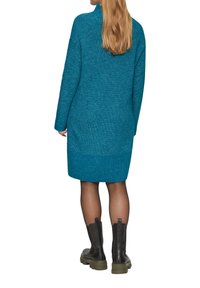 Abito lavorato a maglia color turchese con texture a coste, caratterizzato da maniche lunghe e una linea dritta, abbinato a stivaletti neri con suola spessa.