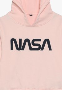 Rózsaszín kapucnis pulóver puha anyagból, elöl kenguruzsebbel. Nagyméretű fekete "NASA" logóval a mellkason. Állítható zsinóros kapucnival.