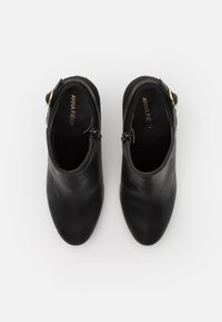 Czarne skórzane botki za kostkę o gładkiej strukturze, z bocznym zamkiem błyskawicznym, małym akcentem klamry i zaokrąglonym noskiem.