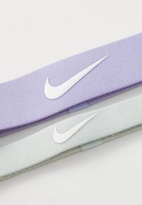 Twee stoffen haarbanden: één lavendel, één mintgroen. Elke haarband heeft een wit Nike swoosh-logo en een textuur met een zachte afwerking.