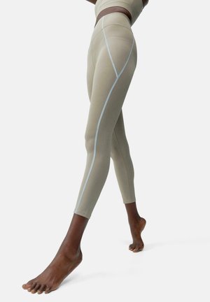 Collants beige clair au design ajusté, avec des détails bleus le long des coutures et une texture lisse pour le confort.