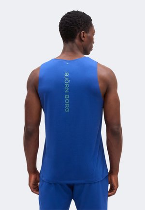 Hombre con camiseta deportiva azul sin mangas y pantalones cortos, de espaldas, con el texto "BJÖRN BORG" en vertical en la parte trasera de la camiseta.