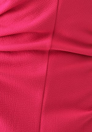 Tessuto fucsia con una superficie testurizzata, caratterizzato da pieghe drappeggiate e delicate creste, che creano profondità visiva e morbidezza.