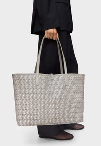 Beige patterned tote bag with grey handles, featuring a geometric design. Made from synthetic material, spacious with a structured shape.