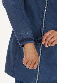 Laivaston säänkestävä takki, jossa on vetoketjusulkeminen, säädettävät tarranauhakämmekkäät ja "PRO 8000" -merkkiteksti hihassa. Sujuva pinta.