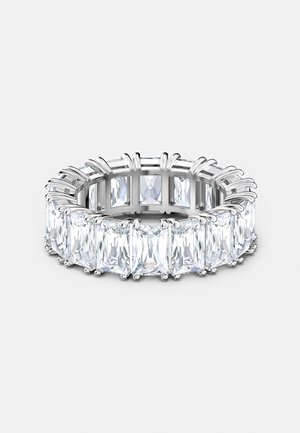 Bague en argent avec de grandes pierres précieuses rectangulaires claires disposées en bande continue sur un fond clair uni.