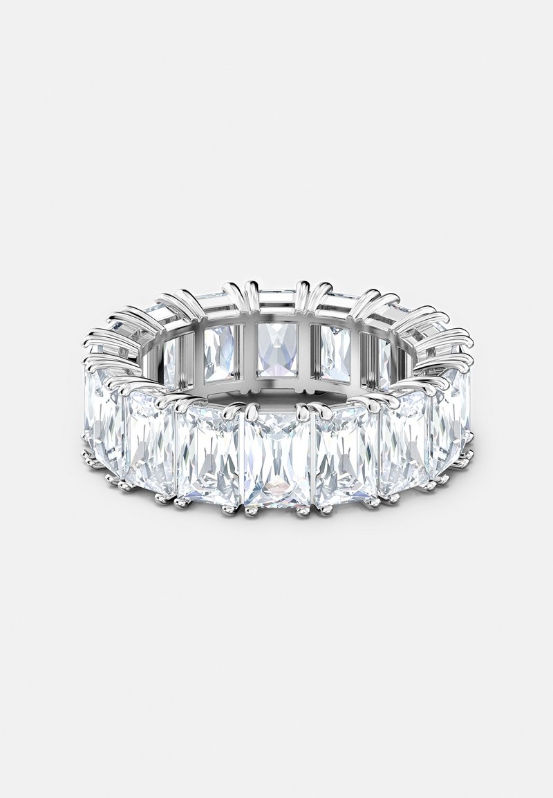 Bague en argent avec de grandes pierres précieuses rectangulaires claires disposées en bande continue sur un fond clair uni.