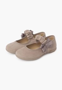 Bailarinas de ante beige con punta redondeada, volantes elásticos y acentos de cinta en el costado. Textura suave y suela de perfil bajo.