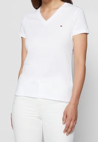 Biała bawełniana koszulka typu V-neck z krótkim rękawem, z małym haftowanym logo na lewej piersi i dopasowanym krojem.