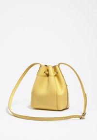 Gelbe Leder-Eimer-Tasche mit einem Kordelzugverschluss, glatter Textur und verstellbarem Trageriemen. Kompakte Form mit einem abgerundeten Boden.