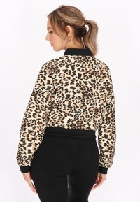 Bomber jacket in stampa leopardata con polsini e orlo in rib elastico neri. Tessuto morbido, silhouette cropped e maniche lunghe. Perfetta per un look casual.