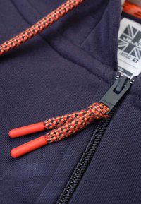 Marineblauwe hoodie met een rits aan de voorkant, voorzien van een gevlochten oranje en zwarte trekkoord met plastic uiteinden, en een stevige ritshendel.
