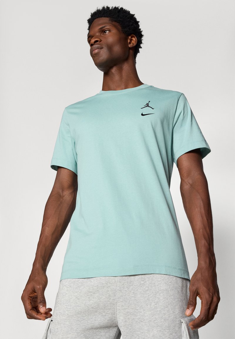Camiseta de manga corta en verde menta de suave tejido; cuenta con un logo negro de Jumpman y la marca Nike en la parte superior izquierda del pecho.