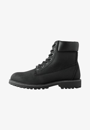 Black leather lace-up ankle boot with padded collar and thick rubber lug sole, shown from the side on a white background.