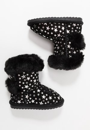 Schwarze Winterstiefel mit silbernen Sternmustern, schwarzem Pelzbesatz und jeweils zwei schwarzen Bommel an jedem Stiefel, vor weißem Hintergrund gezeigt.