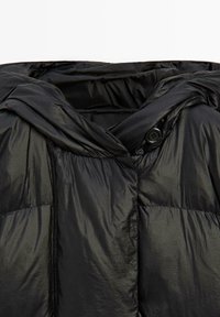 Černá péřová bunda s lesklým povrchem, kapucí a knoflíkovým zapínáním. Texturovaná látka se šitými panely pro izolaci.