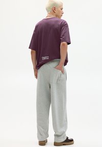 Overdimensioneret lila bomulds t-shirt med rund hals og hvid skrift, parret med lysegrå sweatpants med sidelommer og en afslappet pasform.