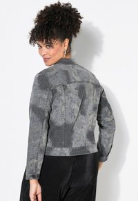 Grå denimjacka med paisleymönster och nitar. Klassisk krage, knappstängning, långa ärmar och en figursydd design.