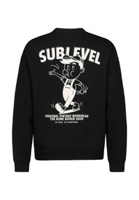 Zwarte sweatshirt met een grote witte grafiek op de achterkant, die een cartoonfiguur in een tuinbroek afbeeldt, met de tekst "SUBLEVEL" erboven.